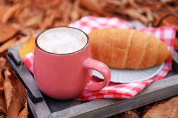 Cup of tasty hot drink and fresh croissant