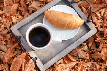 Cup of tasty hot drink and fresh croissant