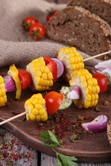 Sliced vegetables on wooden picks and bread on table close-up