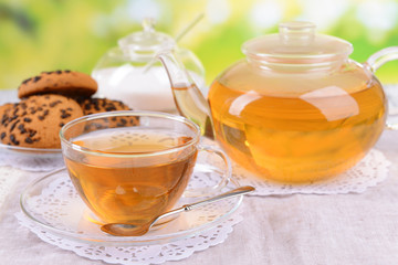 Teapot and cup of tea on table on bright background