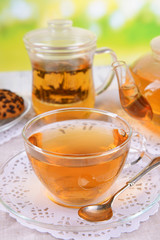 Teapot and cups of tea on table on bright background