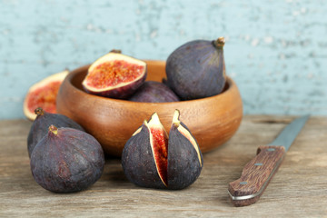 Ripe sweet figs in bowl on wooden background