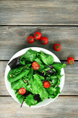 Fresh green salad in bowl on wooden table