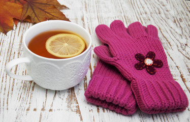 Cup of hot tea with lemon and gloves