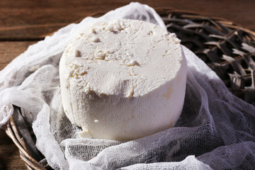 Cottage cheese on gauze on wicker mat on wooden background
