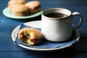 Cup of coffee with tasty cookie on color wooden background