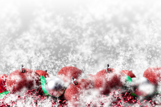 red christmas ornaments and green ribbon in snow