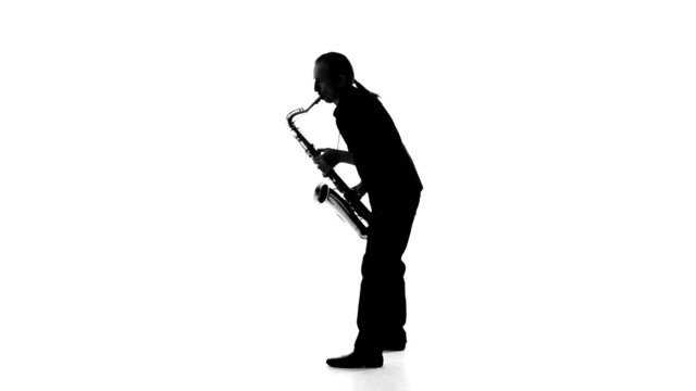 Silhouette of musician emotionally plays the saxophone on a
