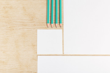 Blanks of empty paper with pencils on a wooden surface.