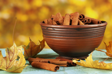 Cinnamon sticks in bowl with yellow leaves