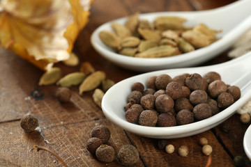 Different spices in spoons with yellow leaves