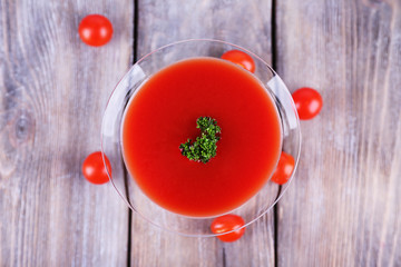 Tomato juice in goblet and fresh tomatoes on wooden background