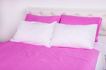 Fototapeta na wymiar Bed in pink bed linen in room