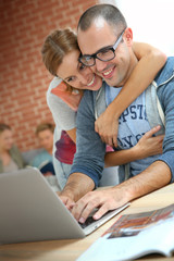 Cheerful couple websurfing on internet with laptop