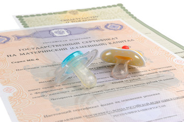 Two baby's dummies with maternal and birth certificates isolated