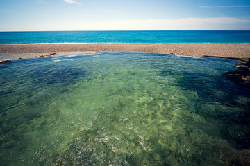 Fototapeta na wymiar Natural pool and river in front of the sea, on Playa San Rafael