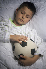 Cute boy asleep with football