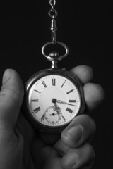 old pocket watch in black and white in human hand