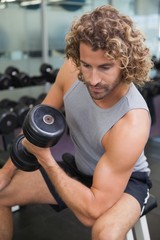 Fototapeta na wymiar Young man exercising with dumbbell in gym