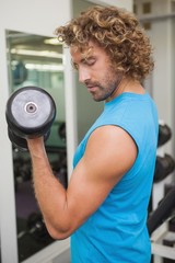 Fototapeta na wymiar Handsome man exercising with dumbbell in gym