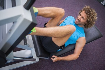 Fototapeta na wymiar Handsome man doing leg presses in gym