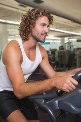 Fototapeta na wymiar Side view of man working out on exercise bike at gym