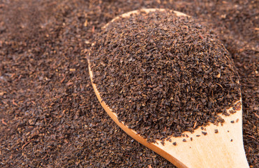 Dried, processed and blended tea leaves in wooden spoon