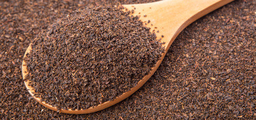 Dried, processed and blended tea leaves in wooden spoon