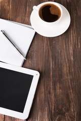 Tablet, paper notebook and coffee on the table