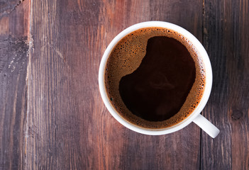 Coffee in the white cup on the wooden table