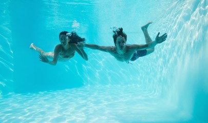 Couple holding hands and swimming underwater