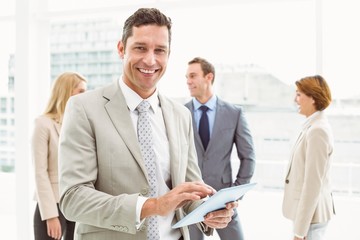 Businessman using digital tablet with colleagues behind