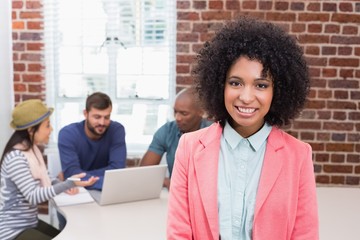 Casual woman with colleagues behind in office
