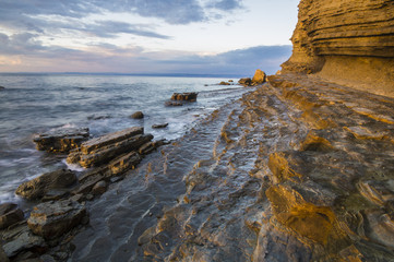 zachód słońca nad morską, skalistą plażą