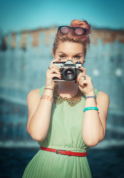 Beautiful girl in vintage clothing making picture with retro cam