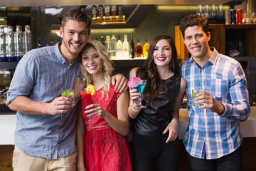 Happy friends smiling at camera holding cocktails
