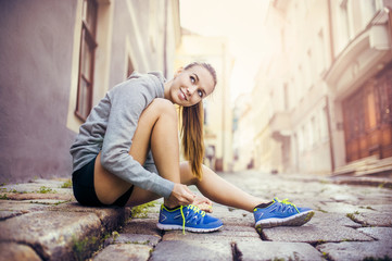 Young female runner tying her shoes