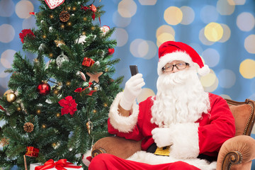 Fototapeta na wymiar santa claus with smartphone and christmas tree