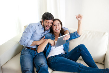 Fototapeta na wymiar young happy couple on couch enjoying digital tablet computer