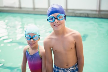 Cute little siblings standing poolside