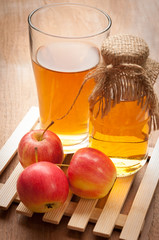 Glasses of apple juice with apples on the background.