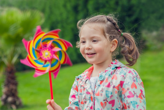 little cute girl playing with pinwheel in nature
