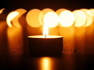 One candle flame at night with bokeh