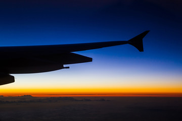Airplane in the sky with skylines and twilight .