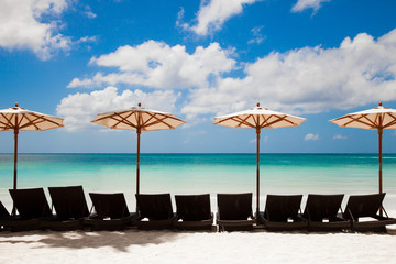 Turquoise sea, deckchairs, white sand and beach umbrellas. Calmn
