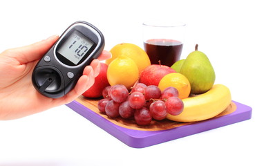 Hand of woman with glucometer and fresh fruits