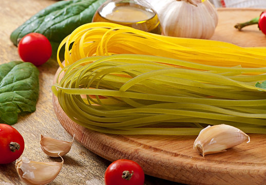 Colorful fettuccine pasta and cooking ingredients on table