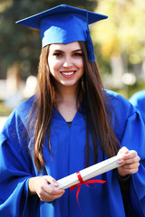 Graduate students wearing graduation hat and gown, outdoors