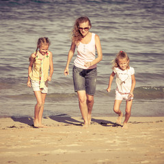 mother and  two daughters playing on the beach