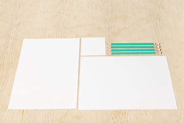 Blanks of empty paper with pencils on a wooden surface.